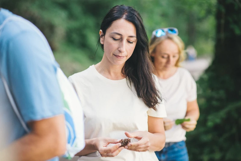 Frau steht draußen in einer gruppe und schaut auf eine kastanie.