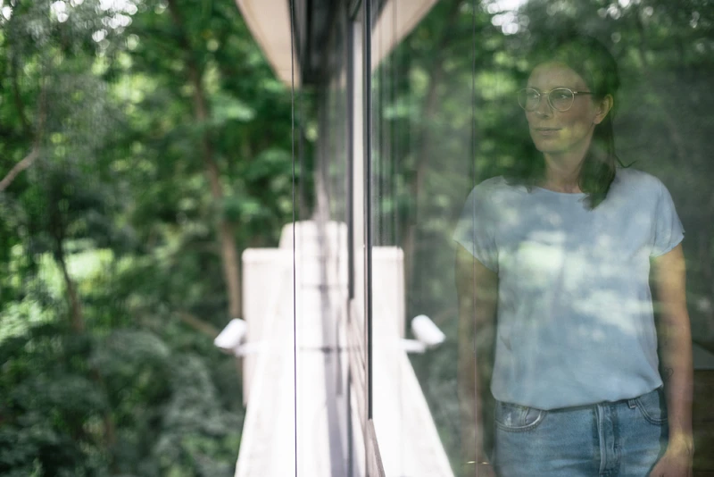 Frau steht vor fenster und schaut nach draußen