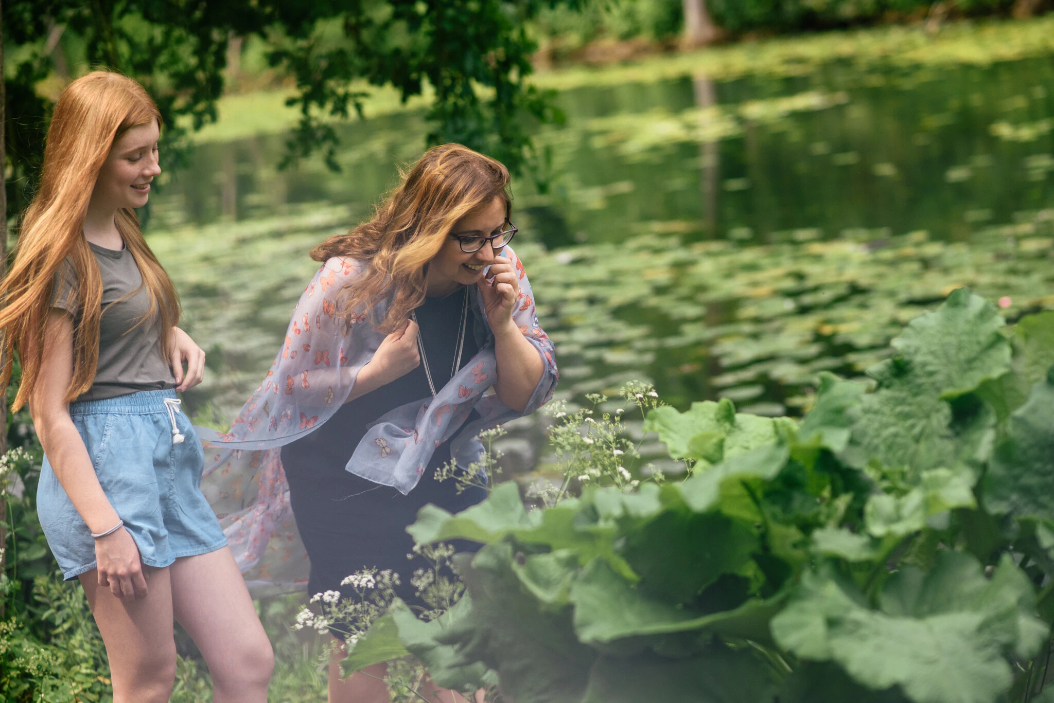 Eine Frau und ein Mädchen spazieren im Wald und beobachten die Natur.