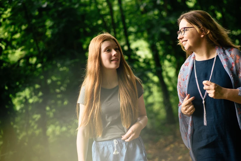 Frau geht mit Mädchen im wald spazieren.