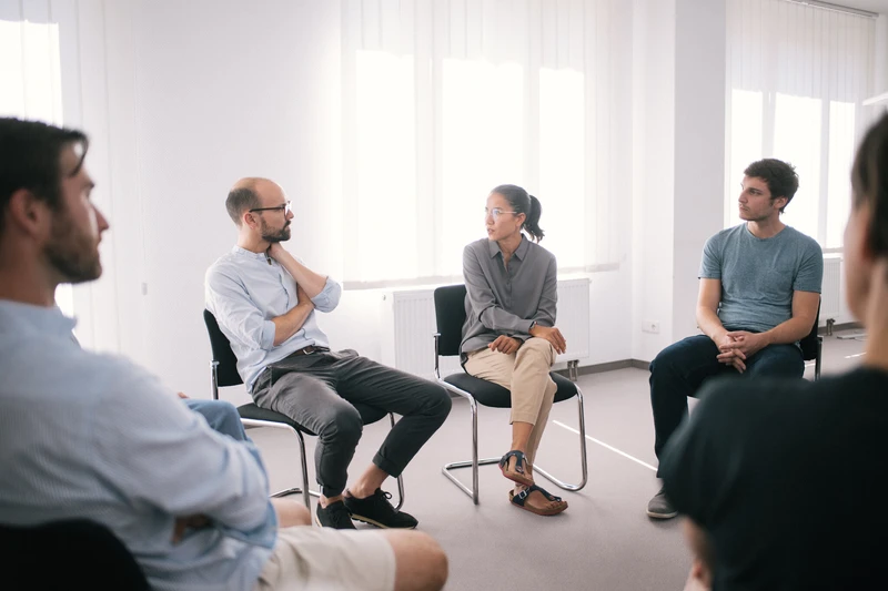 Therapie Gruppe sitzt zusammen in einem hellen weißen raum