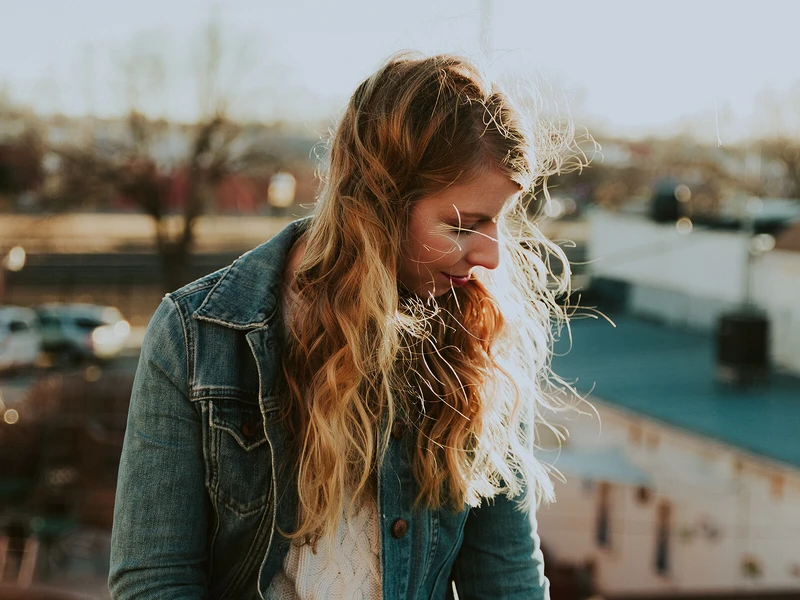 Junge Frau steht draußen im Sonnenlicht