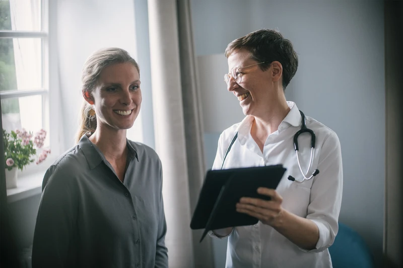 Ärztin im Gespräch mit Patientin, beide lächeln
